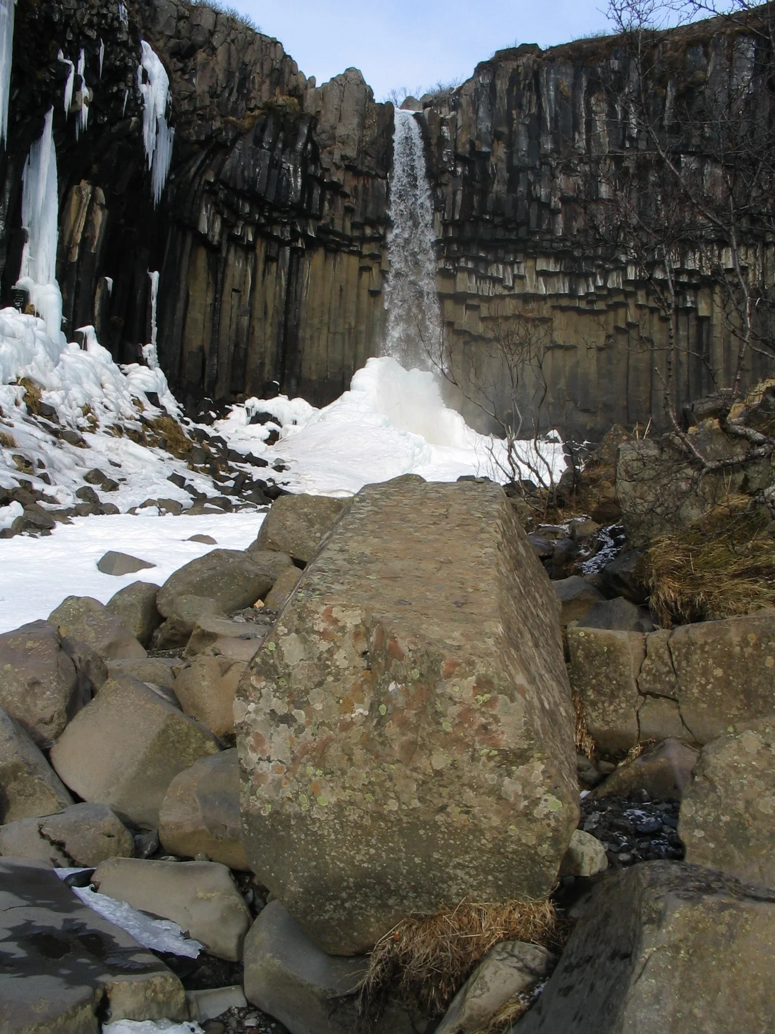 Svartifoss with a large basalt rock in front during winter by photographer Gudrun